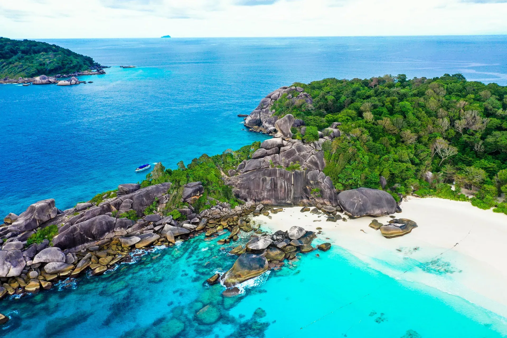 A child paddling a stand-up board across a clear turquoise lagoon enclosed by limestone cliffs
