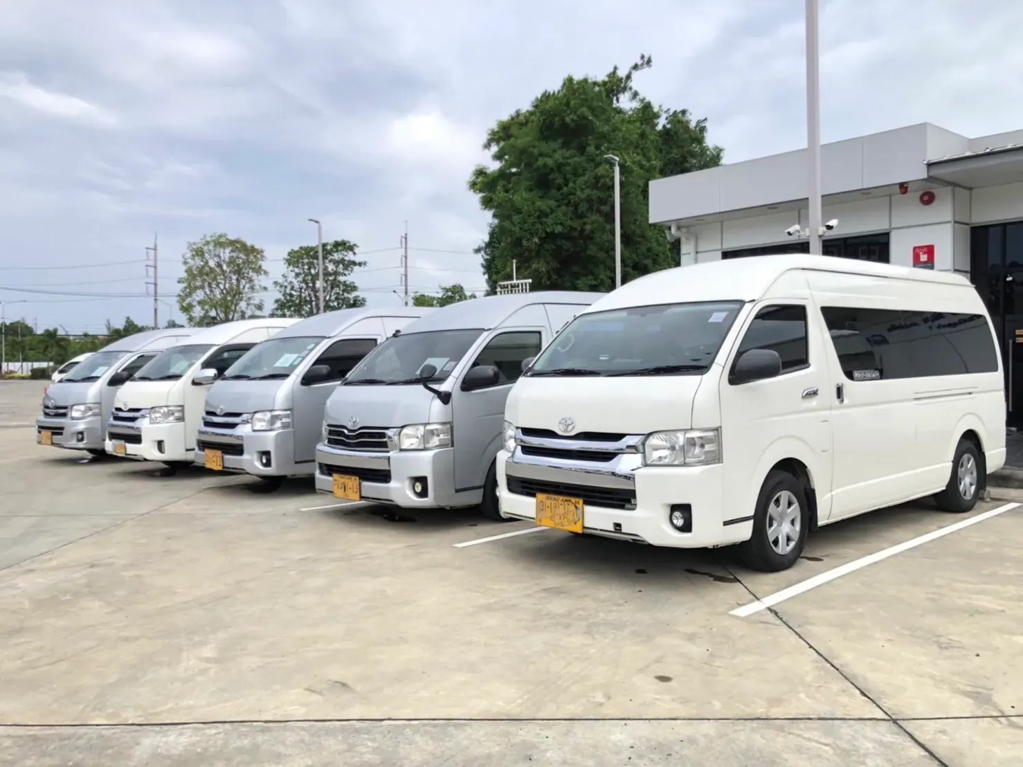 Five white and silver minivans parked in a row at the depot