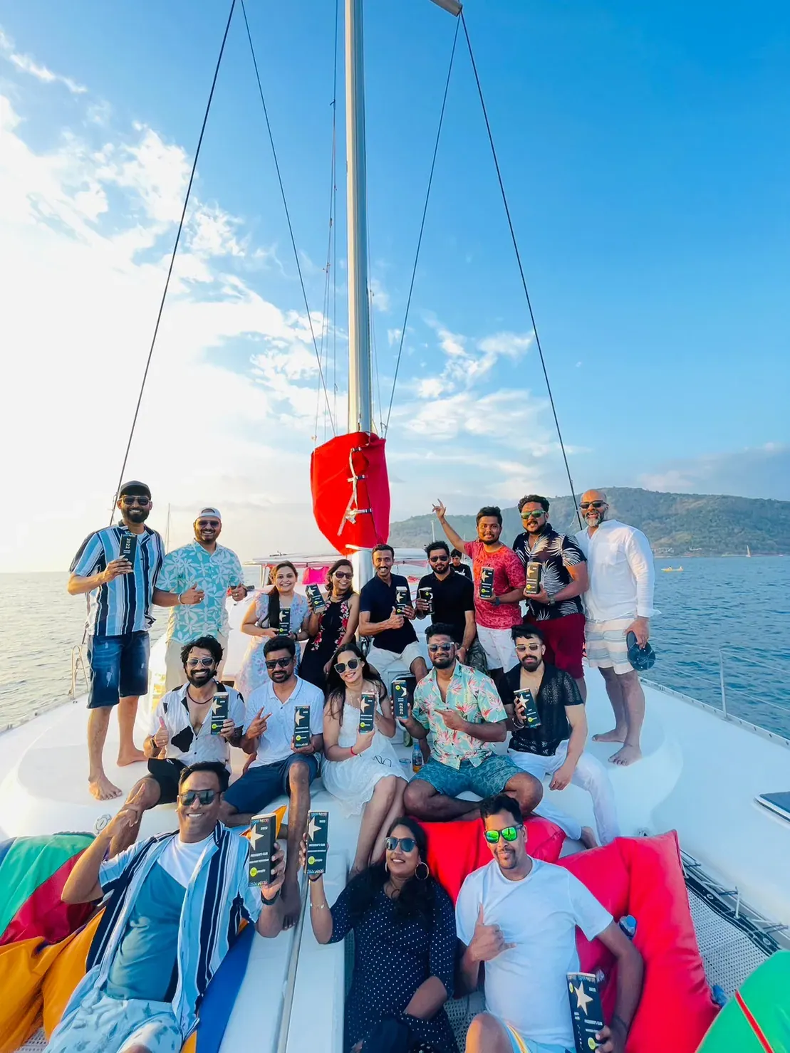 Group of guests celebrating with drinks on a catamaran's bow at a Phuket yacht party