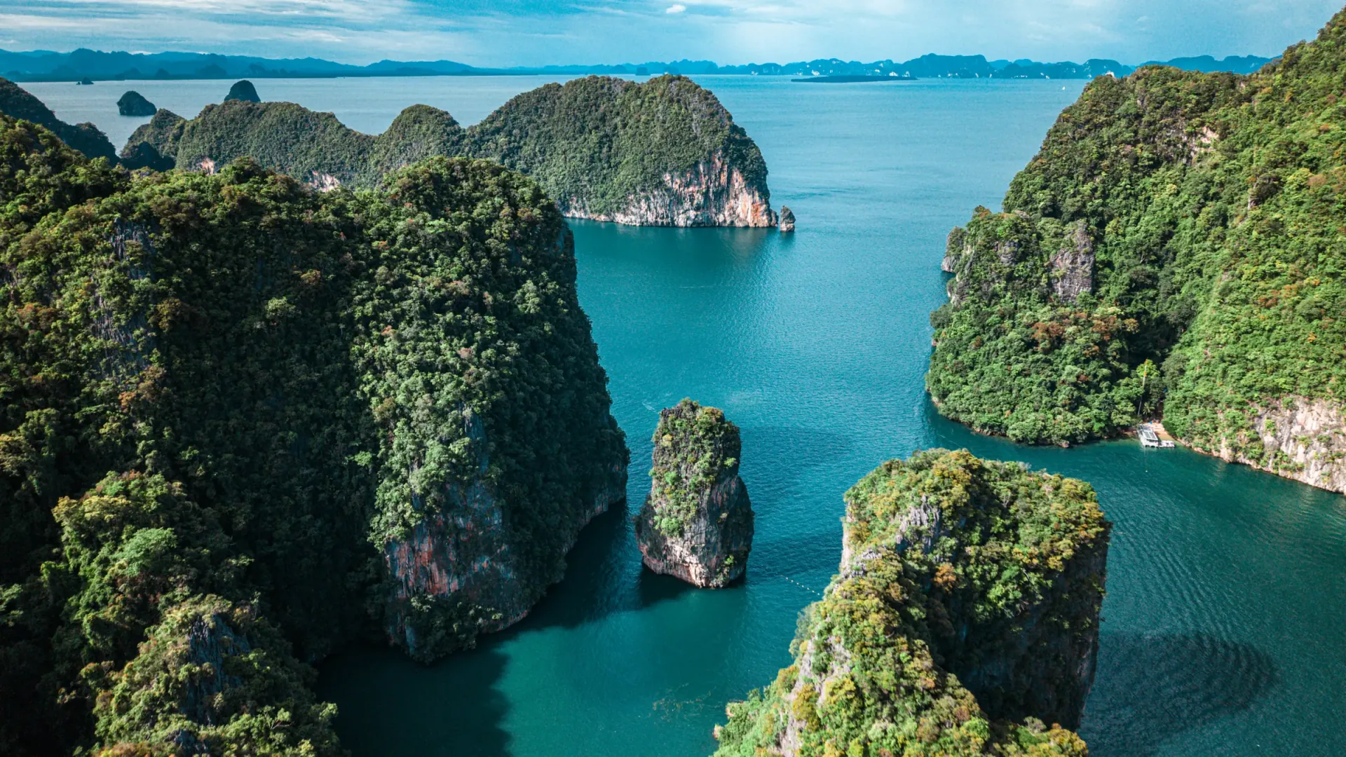 Jungle-covered limestone islands rising out of green water in Phang Nga Bay, seen from the air